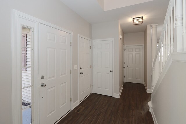 hallway featuring decorative columns and dark hardwood / wood-style flooring