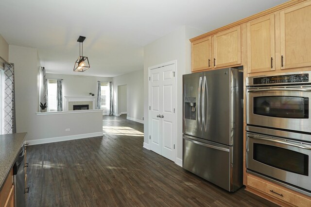 kitchen featuring light brown cabinetry, appliances with stainless steel finishes, dark hardwood / wood-style flooring, and decorative light fixtures