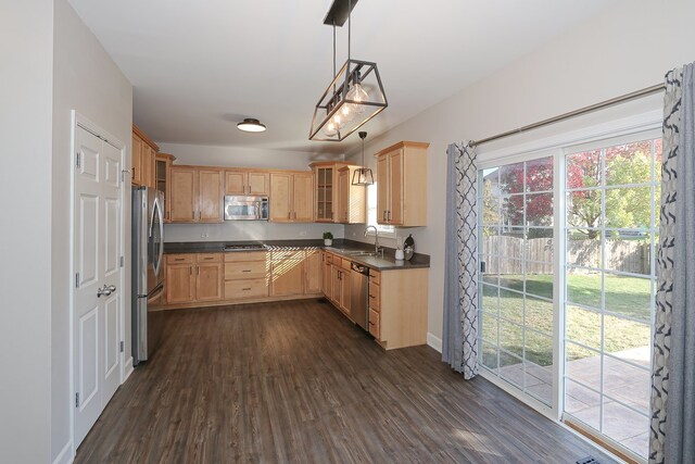 kitchen featuring light brown cabinetry, appliances with stainless steel finishes, sink, decorative light fixtures, and dark wood-type flooring