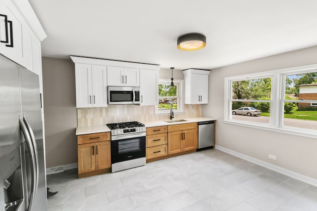 kitchen with sink, tasteful backsplash, decorative light fixtures, white cabinetry, and stainless steel appliances