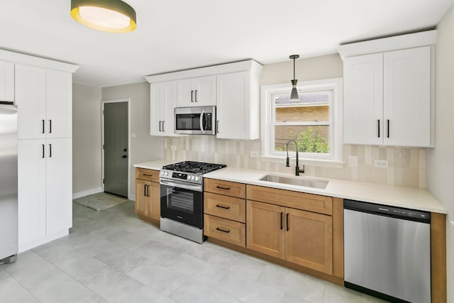 kitchen with backsplash, white cabinets, sink, appliances with stainless steel finishes, and decorative light fixtures