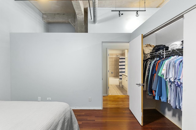 bedroom featuring wood-type flooring, ensuite bathroom, a closet, and track lighting