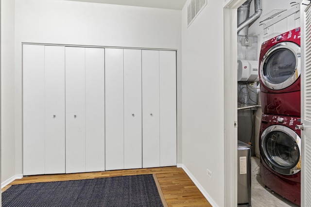 laundry room with light hardwood / wood-style flooring and stacked washer and dryer