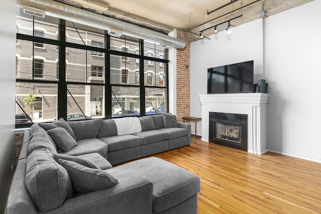 living room featuring a high ceiling, brick wall, and wood-type flooring