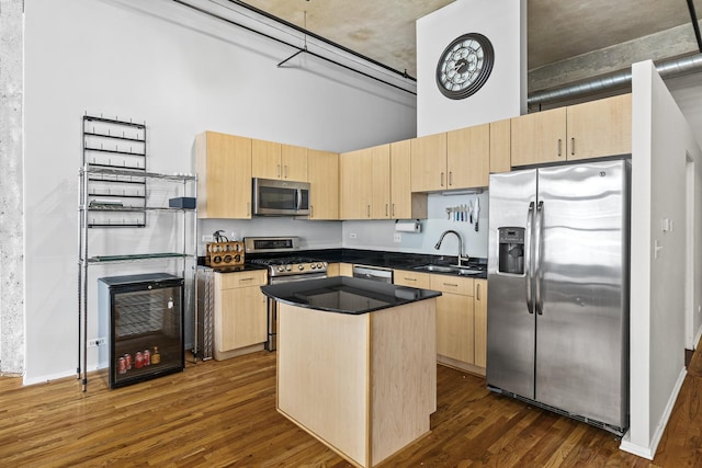 kitchen with light brown cabinetry, sink, appliances with stainless steel finishes, and a center island