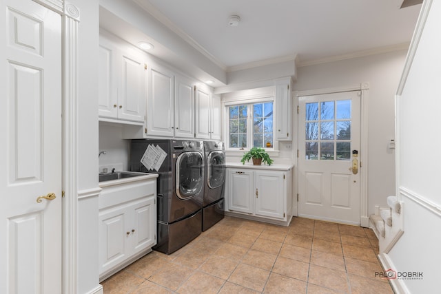 clothes washing area with washer and dryer, sink, crown molding, and cabinets