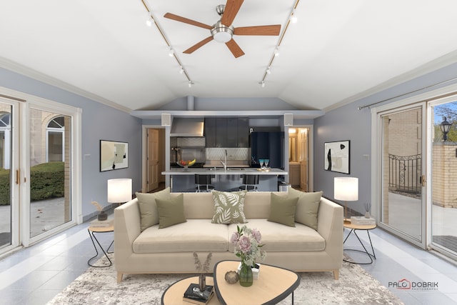 tiled living room with ceiling fan, ornamental molding, rail lighting, and vaulted ceiling