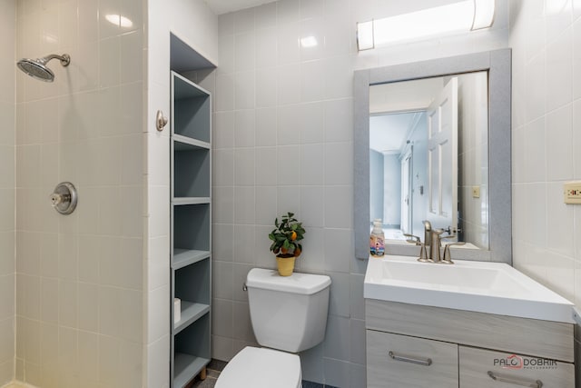 bathroom featuring vanity, toilet, tile walls, and a tile shower