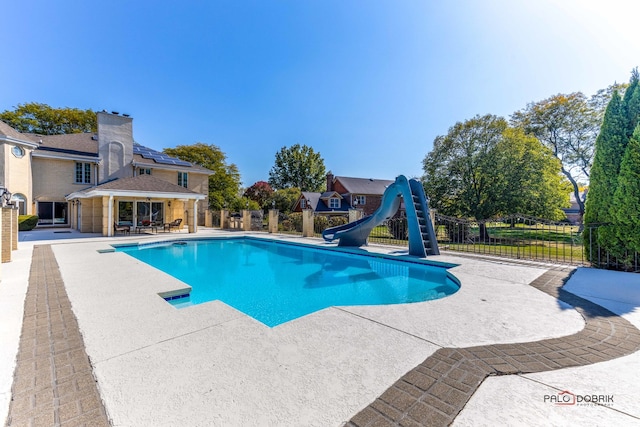 view of pool featuring a water slide and a patio