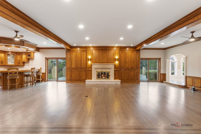 unfurnished living room with crown molding, ceiling fan, and light hardwood / wood-style flooring