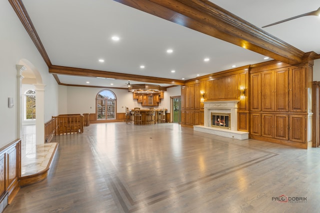 unfurnished living room with crown molding, beam ceiling, wood-type flooring, and decorative columns