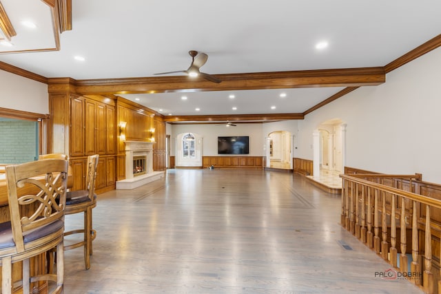 living room featuring beamed ceiling, dark hardwood / wood-style flooring, ornamental molding, and ceiling fan