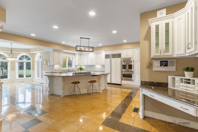 kitchen featuring sink, white cabinetry, hanging light fixtures, a center island, and a kitchen bar