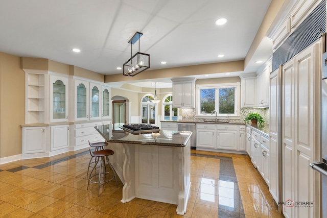 kitchen with decorative light fixtures, white cabinetry, a kitchen breakfast bar, a center island, and stainless steel appliances