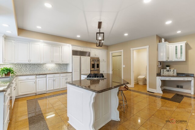 kitchen featuring appliances with stainless steel finishes, decorative light fixtures, a kitchen island, and white cabinets