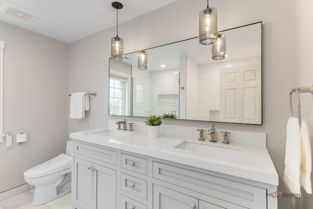 bathroom with vanity, toilet, and tiled shower