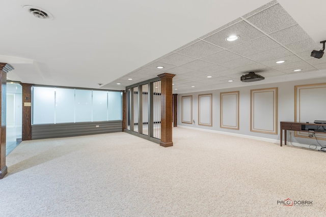 basement with a paneled ceiling and light carpet