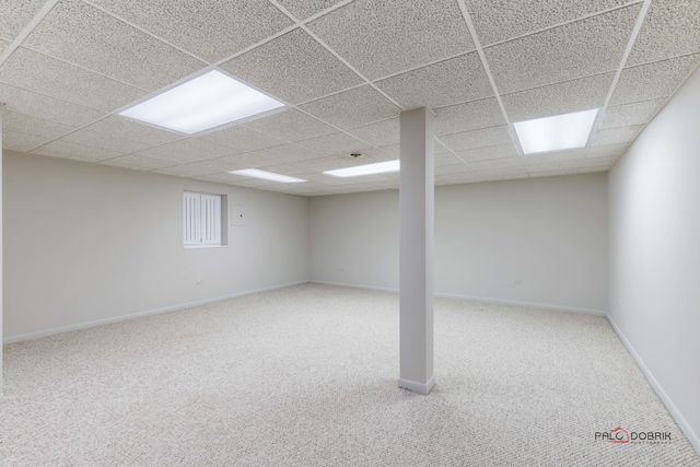 basement with a paneled ceiling and carpet