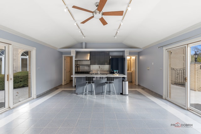 kitchen featuring crown molding, lofted ceiling, a kitchen island with sink, and a breakfast bar area