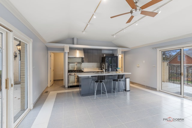 kitchen with a breakfast bar, sink, refrigerator, vaulted ceiling, and a center island with sink