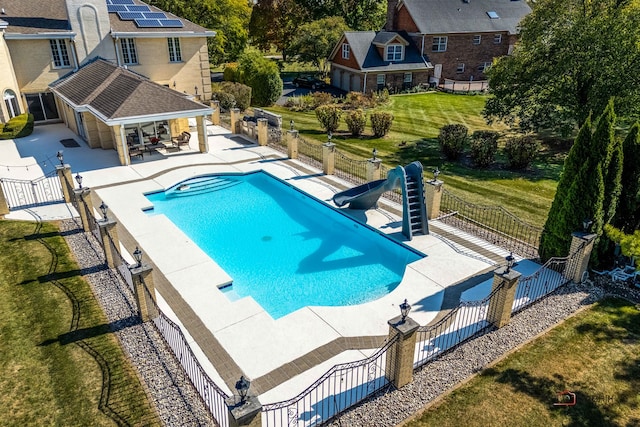 view of swimming pool featuring a patio, a water slide, and a lawn