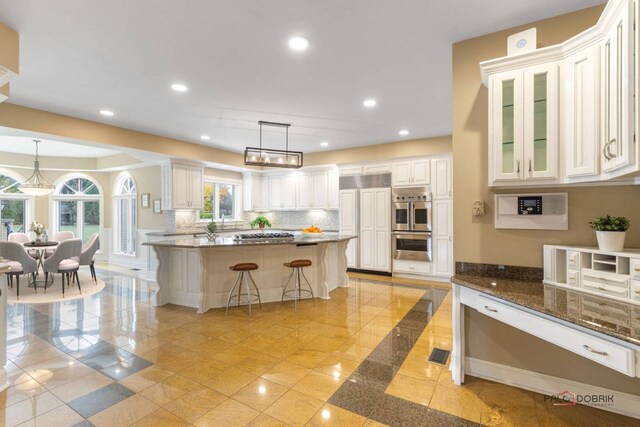 kitchen with a breakfast bar, white cabinetry, hanging light fixtures, a center island, and stainless steel double oven