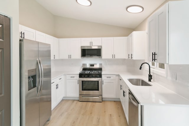 kitchen with sink, white cabinetry, light hardwood / wood-style floors, stainless steel appliances, and lofted ceiling