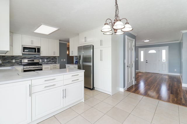 kitchen with appliances with stainless steel finishes, light hardwood / wood-style flooring, decorative light fixtures, and white cabinetry