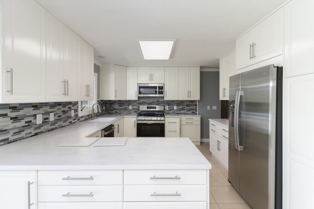 kitchen featuring kitchen peninsula, sink, white cabinetry, light tile patterned floors, and appliances with stainless steel finishes