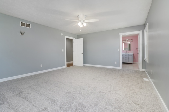 unfurnished bedroom with ensuite bath, light carpet, and ceiling fan