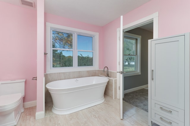 bathroom featuring tile patterned floors, toilet, and a bathing tub