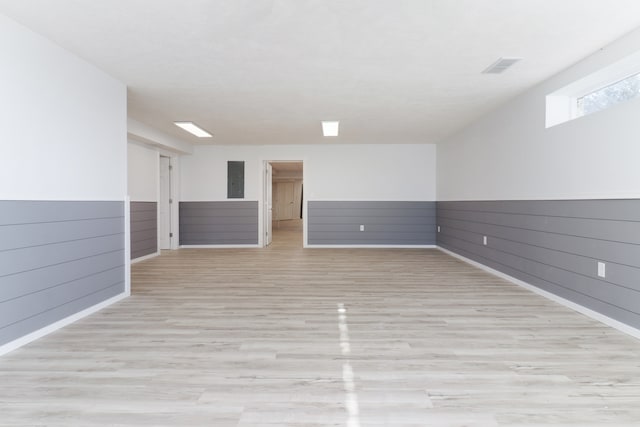 basement featuring light wood-type flooring and wood walls