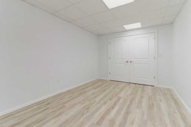 spare room with light hardwood / wood-style flooring and a paneled ceiling