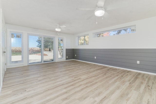 spare room featuring wooden walls and light wood-type flooring