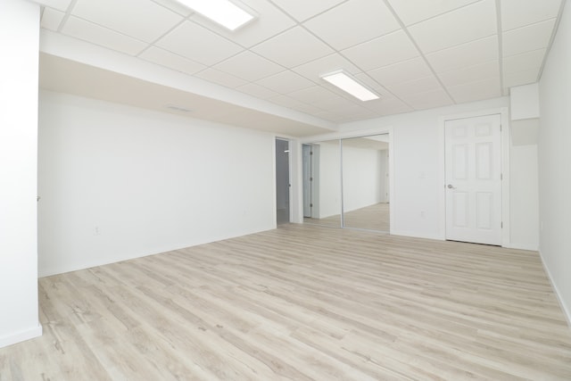 basement featuring a drop ceiling and light hardwood / wood-style flooring