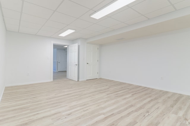 empty room with a drop ceiling and light hardwood / wood-style flooring