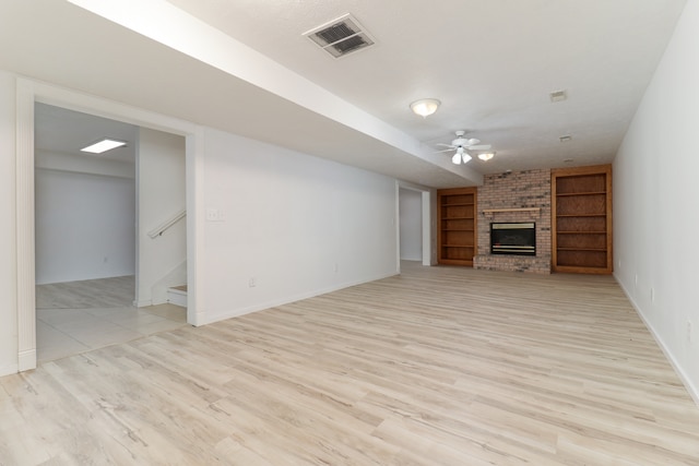 unfurnished living room with a brick fireplace, light hardwood / wood-style floors, and ceiling fan