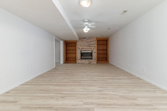 15054 E 2500 N Rd, Hudson, IL 61748 - unfurnished living room featuring a ceiling fan, a fireplace, baseboards, built in features, and light wood-type flooring