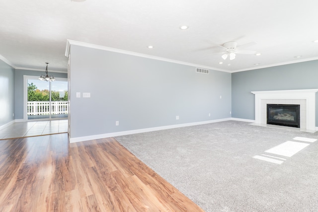 unfurnished living room with crown molding, a tile fireplace, ceiling fan with notable chandelier, and hardwood / wood-style floors