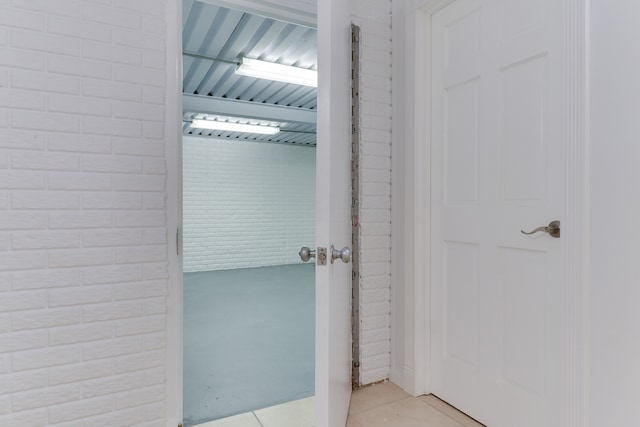 bathroom with brick wall and tile patterned flooring