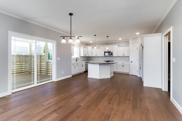 kitchen featuring a center island, white cabinets, dark hardwood / wood-style floors, ornamental molding, and decorative light fixtures