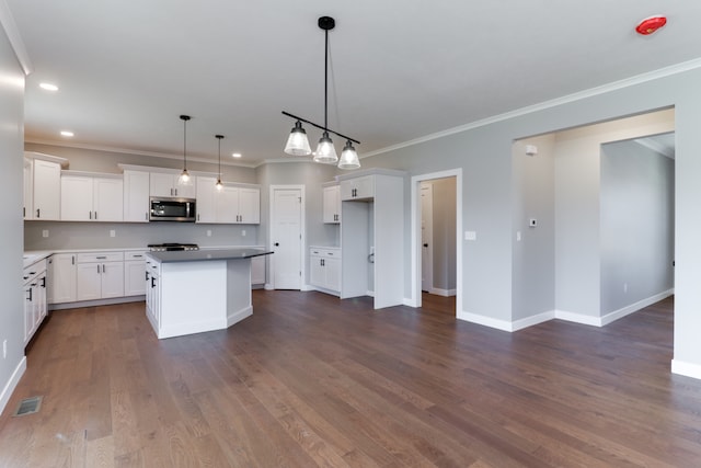 kitchen featuring ornamental molding, dark wood-type flooring, decorative light fixtures, white cabinets, and a center island