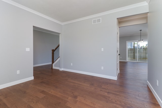 spare room featuring ornamental molding, dark wood-type flooring, and a chandelier