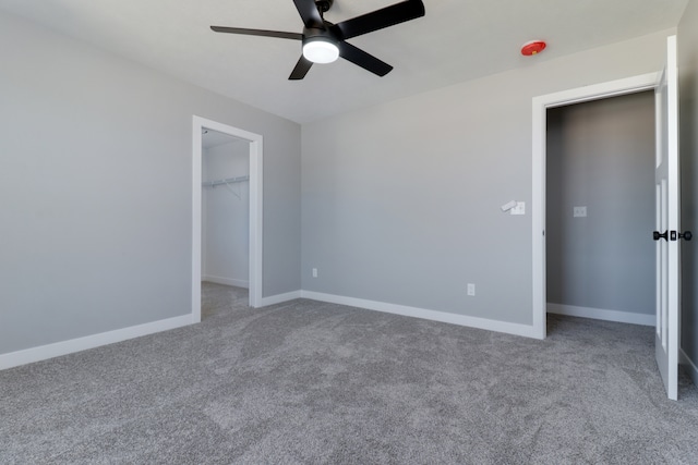 unfurnished bedroom featuring carpet, a closet, a spacious closet, and ceiling fan