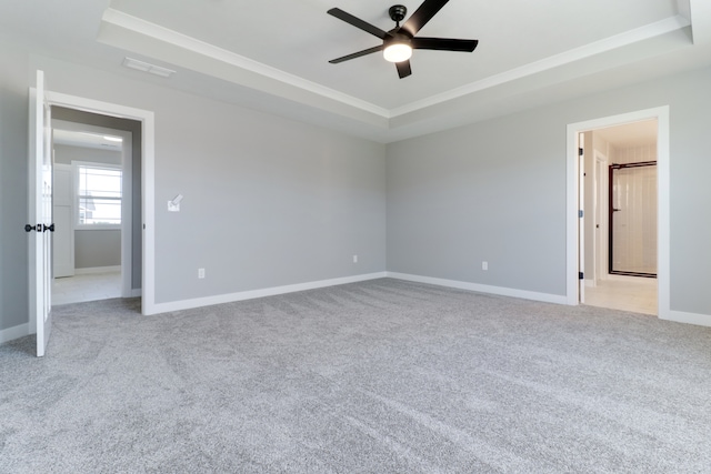 spare room with ceiling fan, light carpet, and a tray ceiling