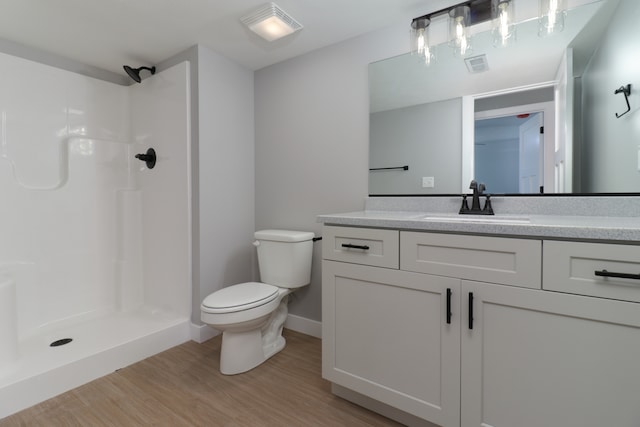 bathroom with toilet, hardwood / wood-style floors, vanity, and walk in shower