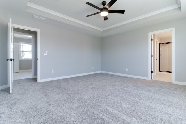 carpeted spare room featuring a raised ceiling and ceiling fan