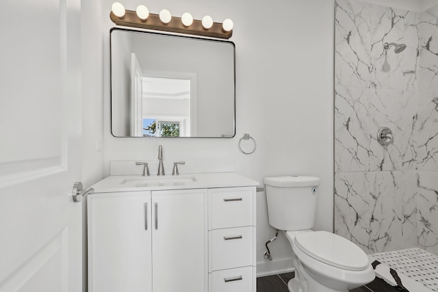 bathroom featuring vanity, a tile shower, and toilet