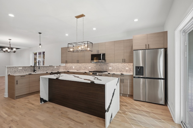 kitchen with a center island, light hardwood / wood-style floors, stainless steel appliances, decorative light fixtures, and an inviting chandelier