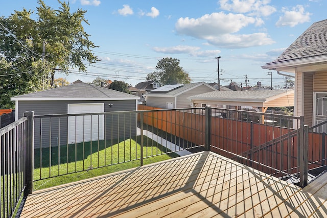 wooden deck featuring a lawn, an outbuilding, and a garage